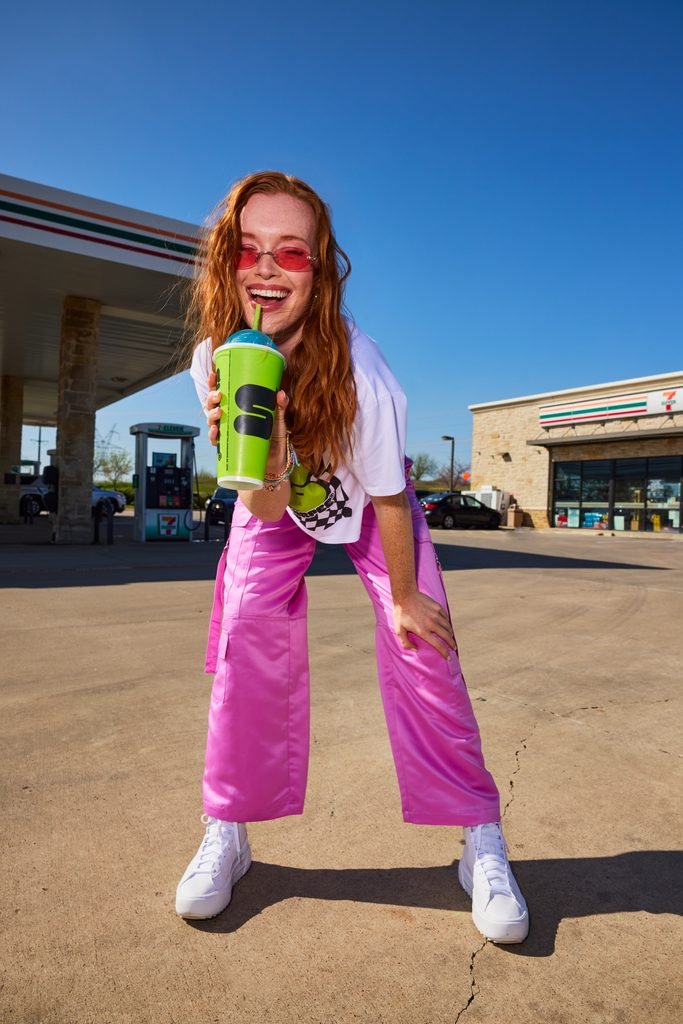 Woman holding a 7-Eleven Slurpee outside a 7-Eleven convenience store