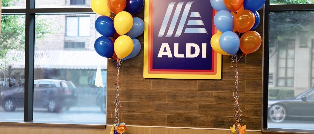 ALDI sign with celebratory balloons ALDI logo sign surrounded by colorful balloons inside an existing store