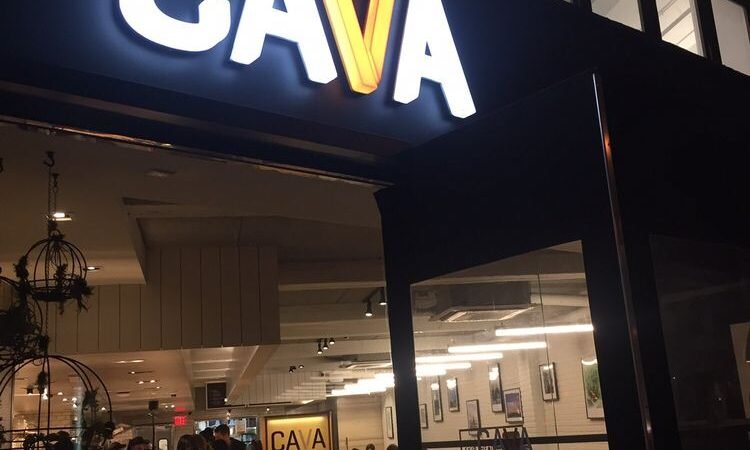 Illuminated CAVA sign above the entrance to an existing restaurant