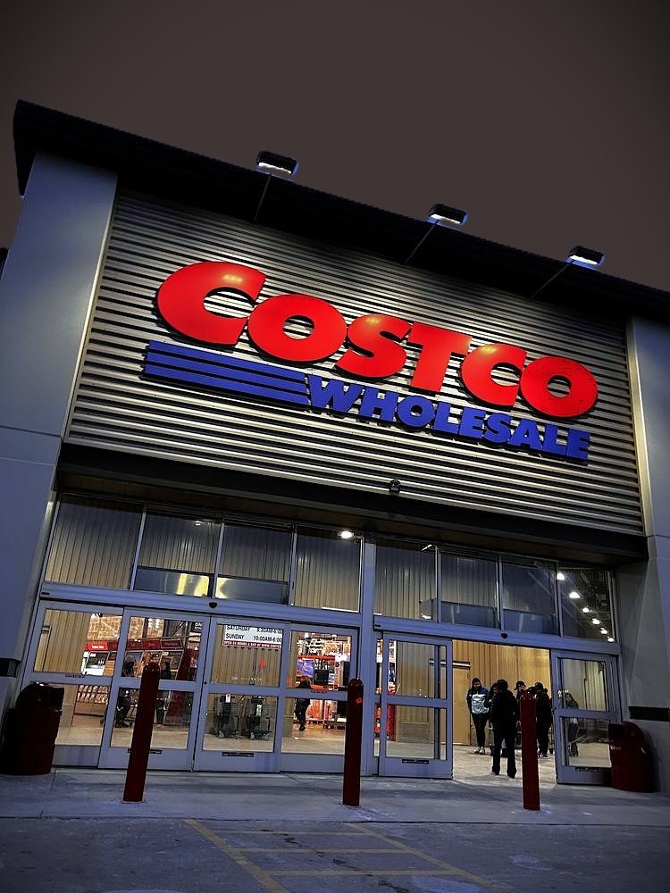 Costco Wholesale sign above the illuminated entrance of an existing warehouse