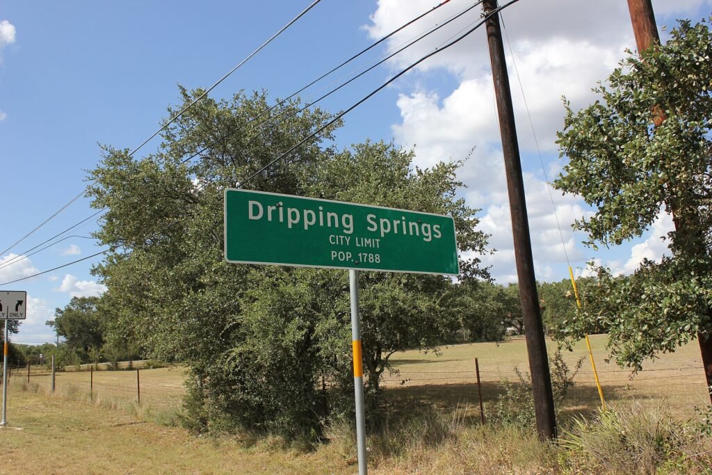Dripping_Springs_City_Limits_(8452118210) Dripping Springs City Limit Sign with population notated.