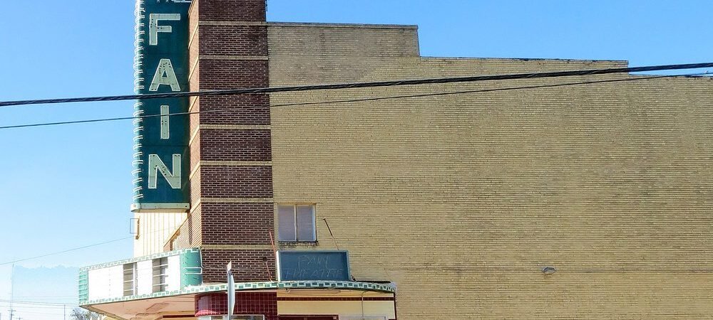 Fain Theater in Livingston with its green vertical sign, marquee, and corner ticket booth