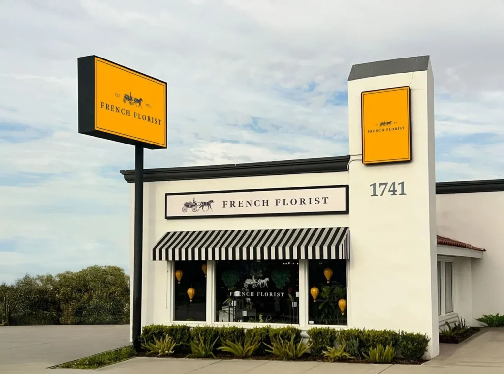 French Florist storefront with yellow signs and a striped awning