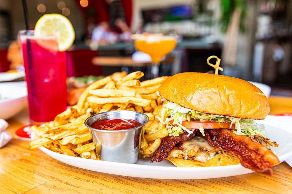 Bacon-topped sandwich with fries and drinks at HG Sply Co.