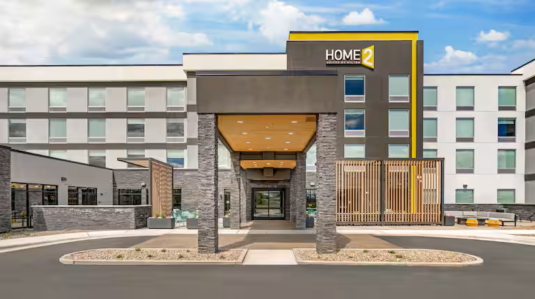Home2 Suites hotel exterior with a covered entrance and yellow architectural accents.