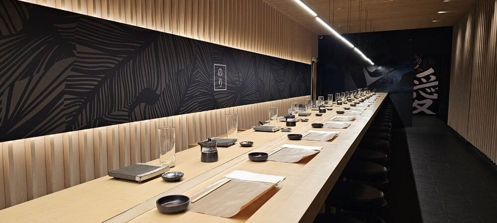 Nori Handroll Bar Counter Interior Nori Handroll Bar interior with a long wooden dining counter and overhead lighting.
