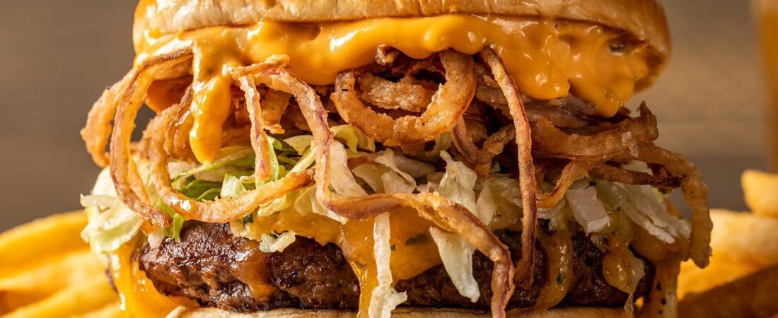 Oak & Stone cheeseburger with crispy onion straws, lettuce, and fries