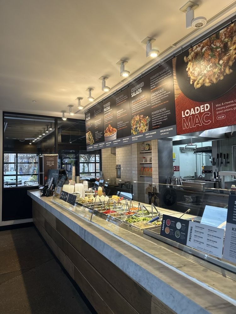 Piada restaurant counter with fresh ingredients, menu boards, and an open kitchen.
