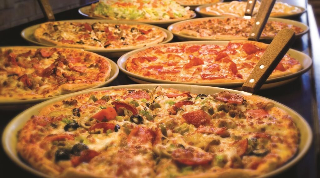 Assorted pizzas with cheese, meat, and vegetable toppings on a Pizza Ranch buffet.