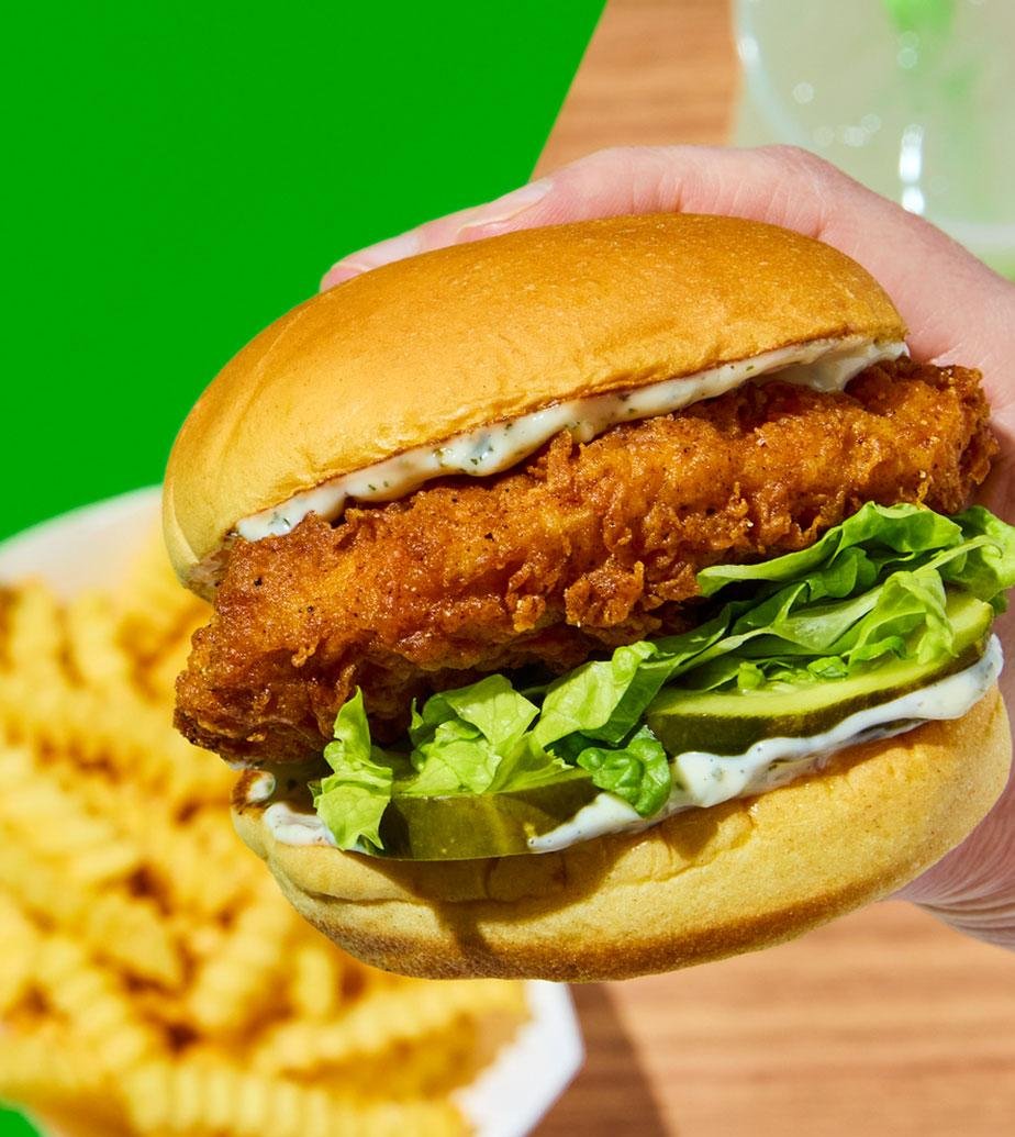 Shake Shack Crispy Chicken Sandwich Shake Shack crispy chicken sandwich with lettuce, pickles, and herb sauce on a bun.