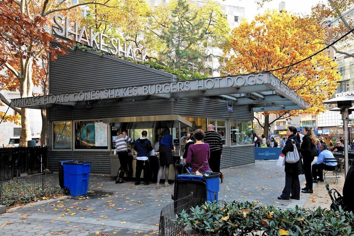 Shake Shack - Madison Square Park Shake Shack kiosk surrounded by trees and outdoor tables in Madison Square Park in New York City