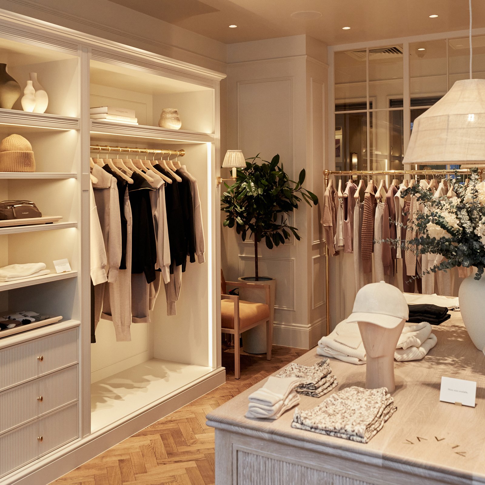Existing Varley store interior with neutral clothing displays, warm lighting, and pale cabinetry