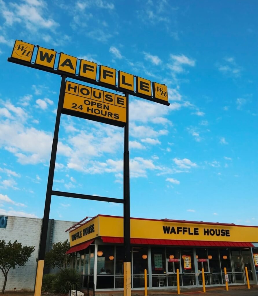 Waffle House restaurant exterior with a yellow roadside sign and red awnings
