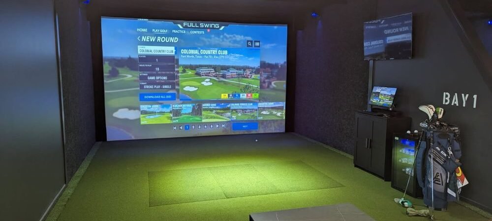 Back Nine Golf simulator bay with a Full Swing screen, hitting mat and golf clubs