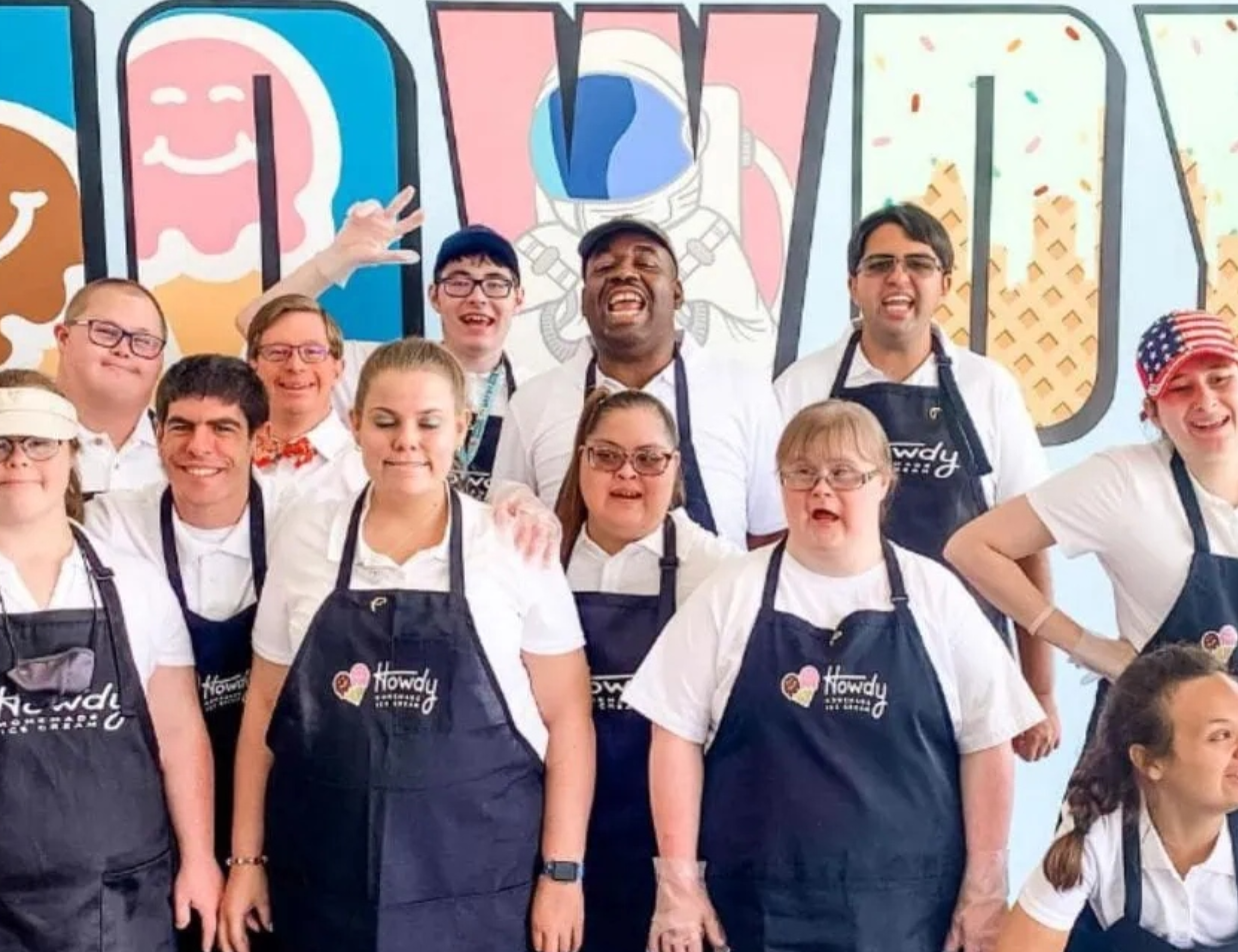 Howdy Homemade team members posing together in front of a colorful mural