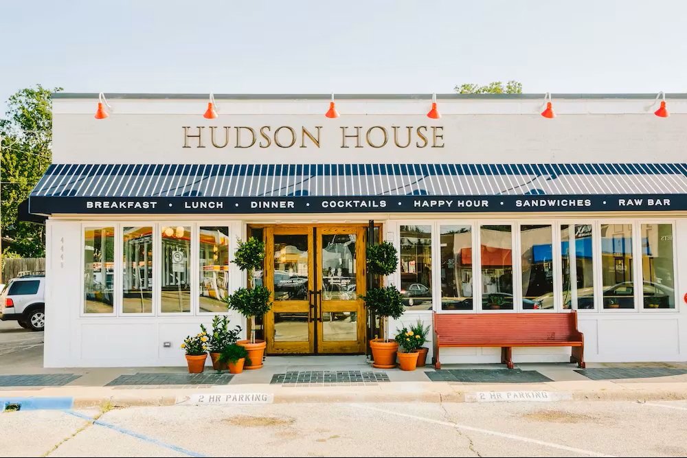Exterior of an existing Hudson House restaurant with striped awning and gold lettering
