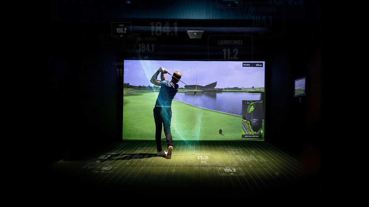 Indoor Golf Simulator Practice Golfer completing a swing in an indoor golf simulator with a virtual course and shot data