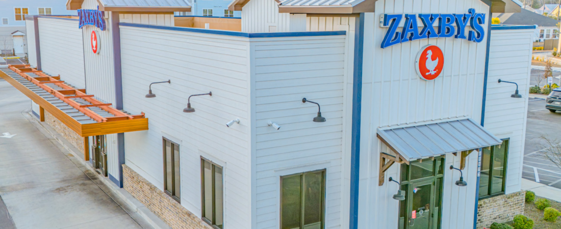Zaxby's restaurant exterior with white siding, metal roof accents and blue signs